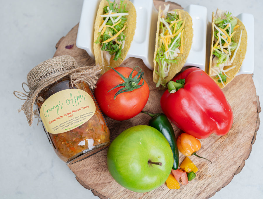 Apple Peach Salsa beside tacos, peppers, tomatoes and a green apple