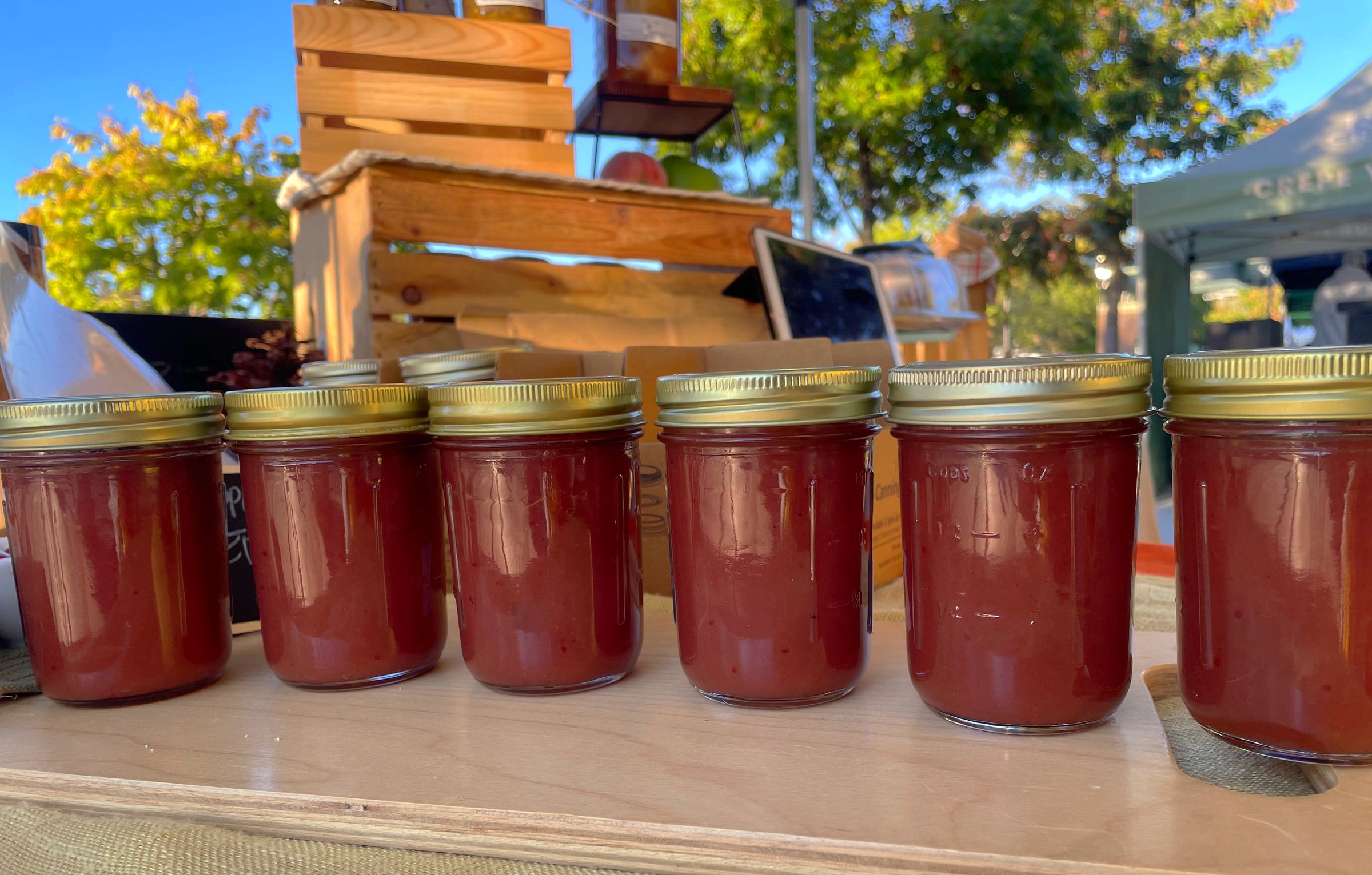 Jars of Ginny's Apples lined up at an outdoor market