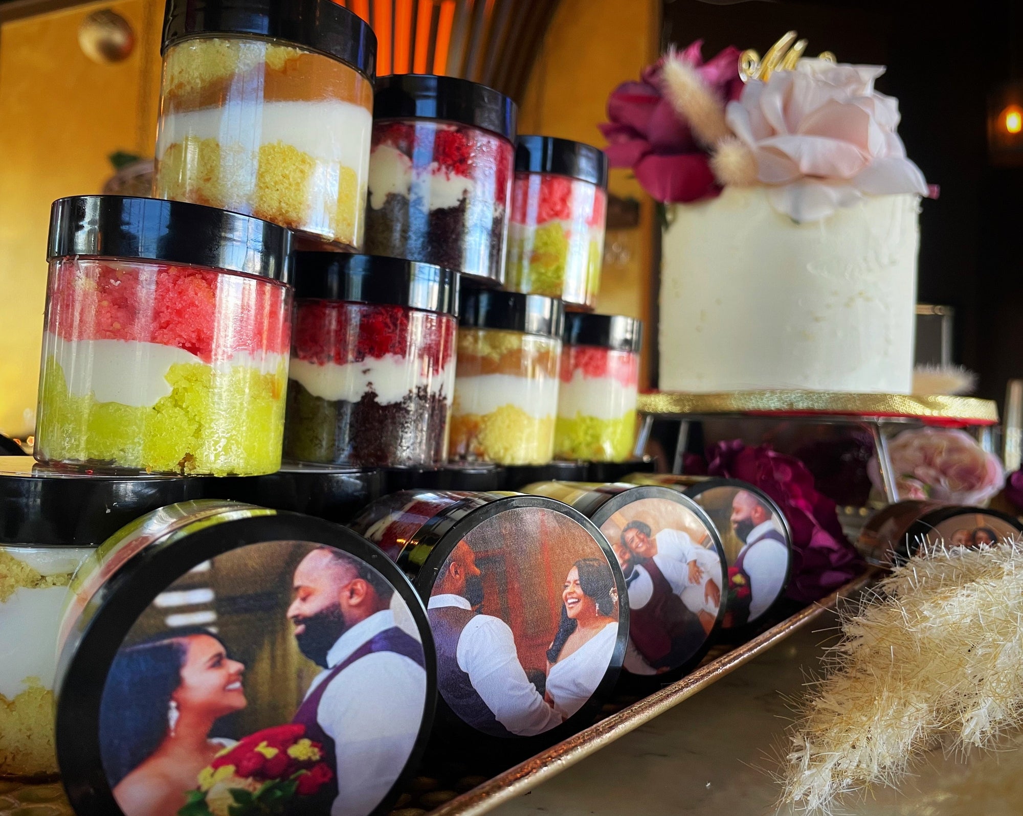 Mini cake jars with custom photo toppers on a shelf
